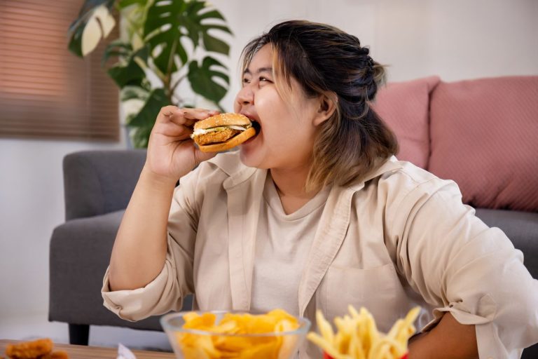 Happy Asian fat woman enjoy eating delicious hamburger on living